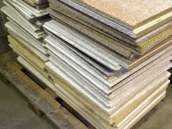 Stack of OSB/ plywood panels stacked on a wooden pallet in a workshop or warehouse storage area